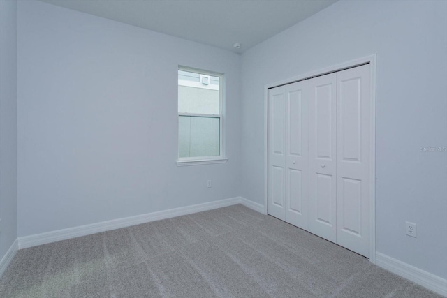 unfurnished bedroom featuring light carpet and a closet