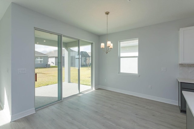 unfurnished dining area with a notable chandelier and light hardwood / wood-style floors