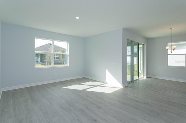 spare room with a notable chandelier and light wood-type flooring