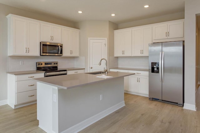 kitchen with appliances with stainless steel finishes, an island with sink, white cabinetry, and sink