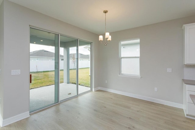 unfurnished dining area with light hardwood / wood-style floors and a notable chandelier