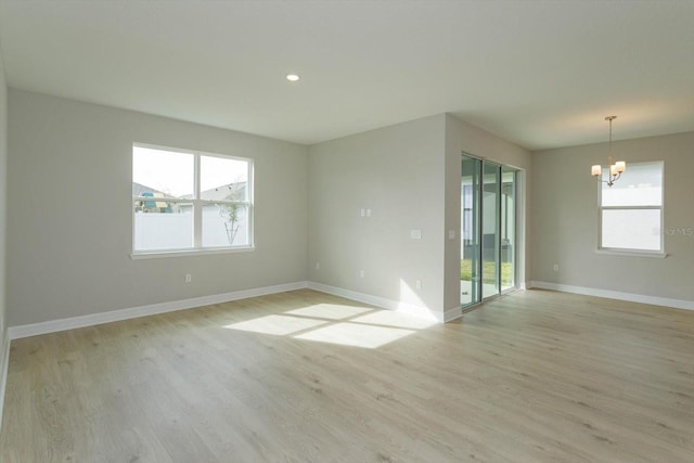 spare room featuring light hardwood / wood-style flooring and a notable chandelier