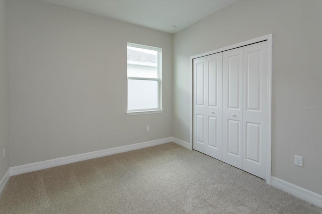 unfurnished bedroom with a closet and light colored carpet