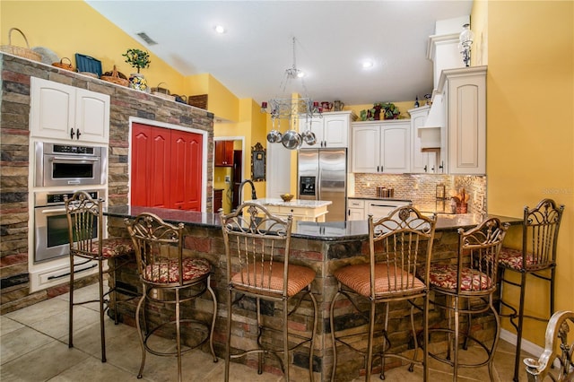 kitchen with a kitchen bar, backsplash, stainless steel appliances, a kitchen island, and lofted ceiling