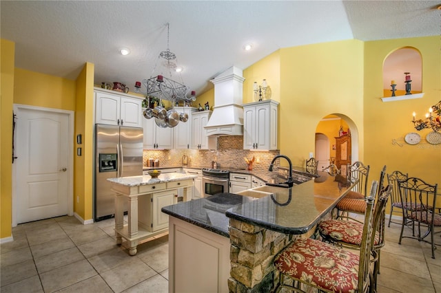 kitchen featuring kitchen peninsula, appliances with stainless steel finishes, decorative backsplash, a breakfast bar, and sink