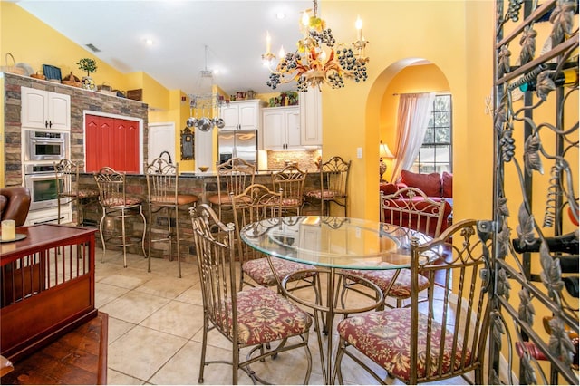 dining room with light tile patterned floors, lofted ceiling, and a notable chandelier