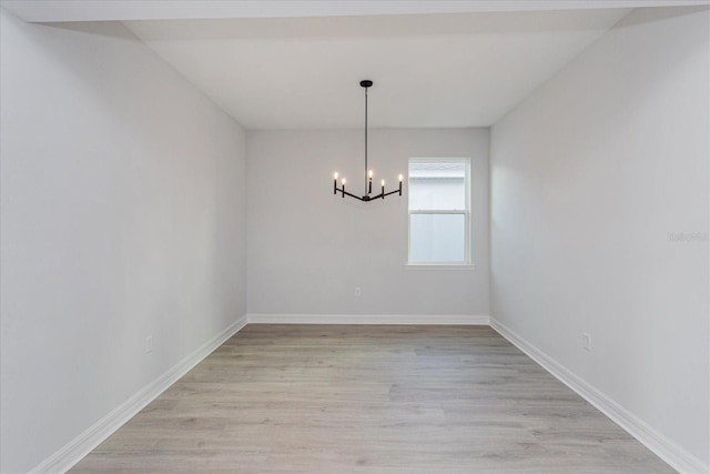 unfurnished dining area featuring an inviting chandelier and light hardwood / wood-style flooring