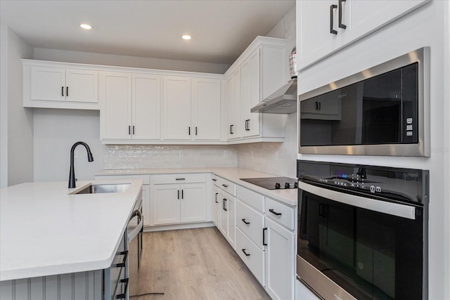 kitchen featuring stainless steel appliances, white cabinetry, tasteful backsplash, and sink