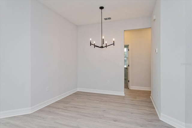 unfurnished dining area with a notable chandelier and light wood-type flooring