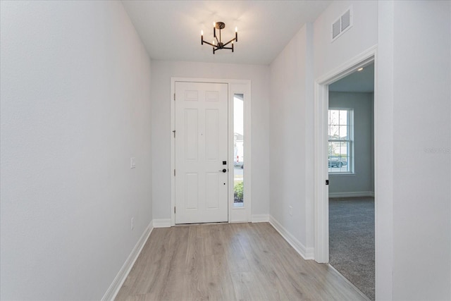 foyer featuring light hardwood / wood-style floors, an inviting chandelier, and a healthy amount of sunlight