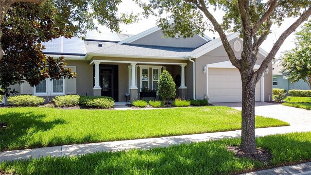 view of front facade featuring solar panels, a porch, a garage, and a front yard