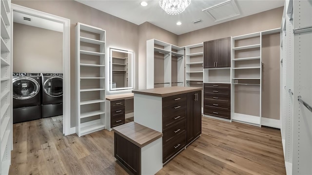 walk in closet with an inviting chandelier, washing machine and clothes dryer, and light hardwood / wood-style floors