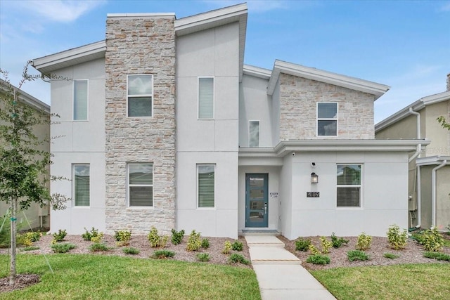 view of front of property featuring a front lawn, stone siding, and stucco siding