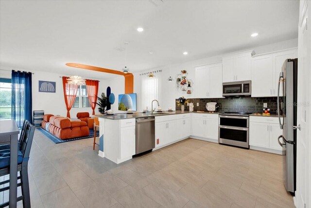 kitchen featuring stainless steel appliances, light tile patterned floors, decorative backsplash, sink, and kitchen peninsula