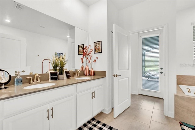 bathroom with tiled bath, dual vanity, and tile patterned flooring