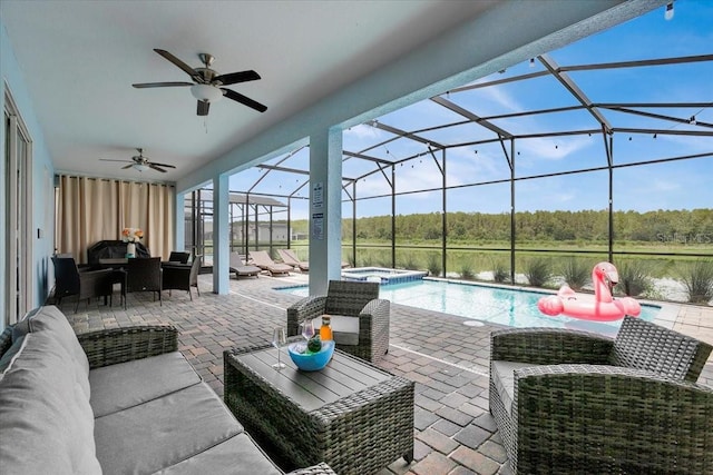 view of patio featuring a ceiling fan, a pool with connected hot tub, glass enclosure, a wooded view, and an outdoor hangout area