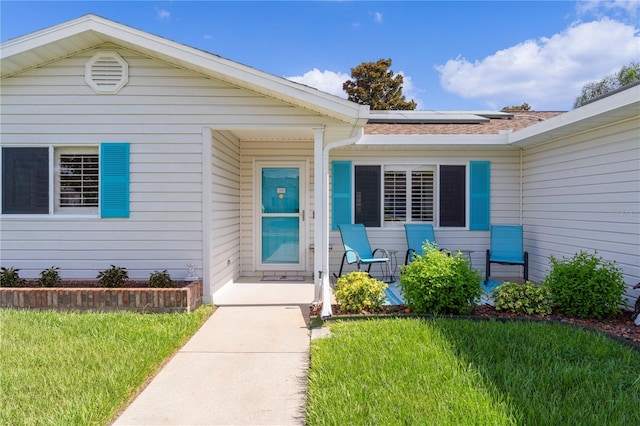 view of exterior entry featuring solar panels and a yard