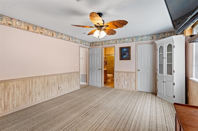 unfurnished bedroom featuring light colored carpet, ensuite bath, and ceiling fan