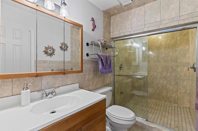 bathroom with tile walls, tasteful backsplash, toilet, a shower with door, and vanity