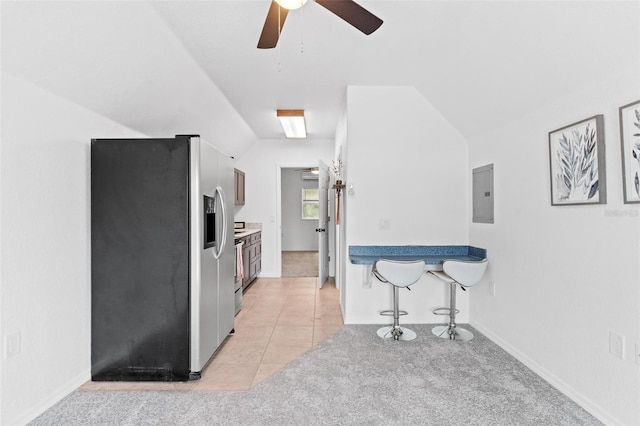 kitchen featuring ceiling fan, stainless steel refrigerator with ice dispenser, light tile floors, a breakfast bar, and lofted ceiling