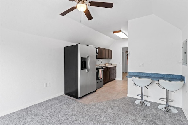 kitchen featuring a kitchen breakfast bar, lofted ceiling, appliances with stainless steel finishes, dark brown cabinetry, and ceiling fan