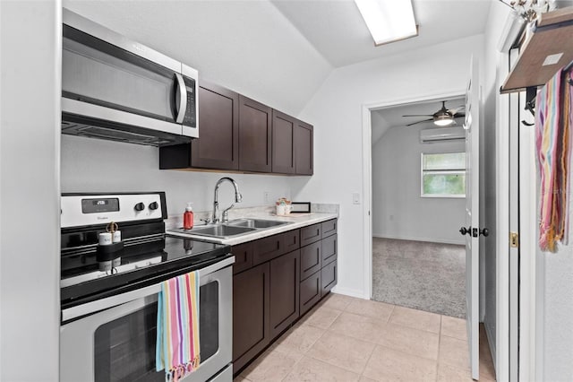 kitchen featuring lofted ceiling, appliances with stainless steel finishes, sink, ceiling fan, and light tile floors