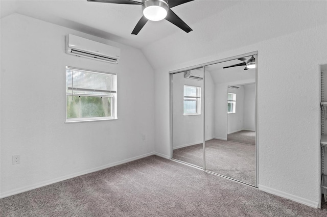 unfurnished bedroom featuring ceiling fan, a closet, carpet floors, a wall mounted AC, and vaulted ceiling