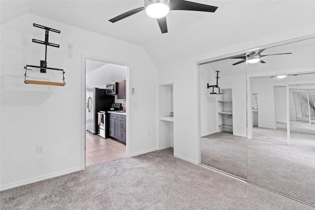 unfurnished bedroom featuring ceiling fan, light tile flooring, stainless steel refrigerator, and lofted ceiling