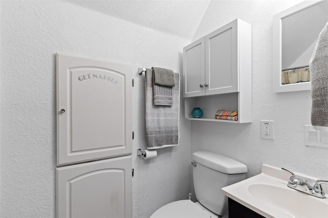 bathroom with vaulted ceiling, vanity with extensive cabinet space, and toilet