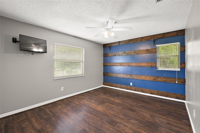 empty room with ceiling fan, a textured ceiling, and dark wood-type flooring