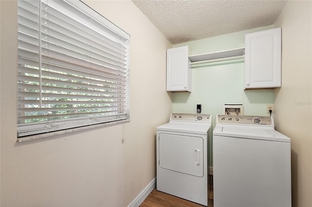 laundry area featuring cabinets, a textured ceiling, washing machine and dryer, and dark wood-type flooring