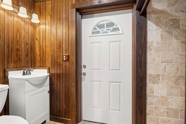 bathroom featuring vanity, toilet, and wooden walls