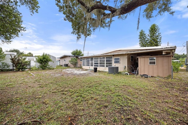 back of house featuring central AC, a sunroom, and a yard