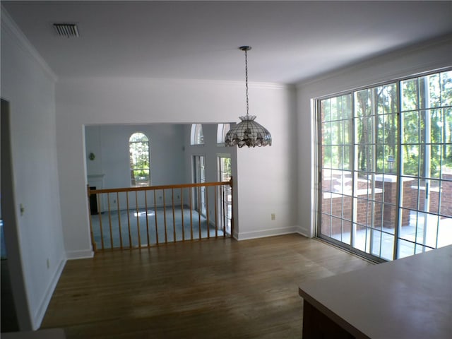 unfurnished dining area featuring plenty of natural light, dark wood-type flooring, and crown molding