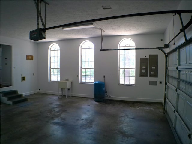 garage featuring electric panel, sink, and a garage door opener