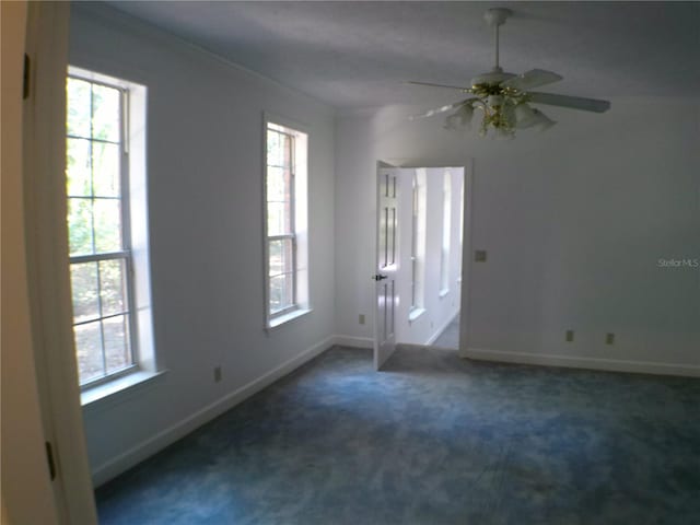 spare room featuring dark carpet, ceiling fan, and ornamental molding