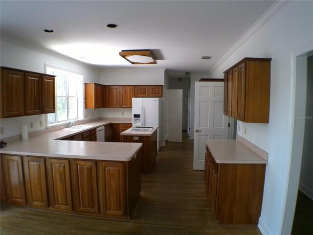 kitchen featuring white appliances, sink, dark wood-type flooring, kitchen peninsula, and ornamental molding