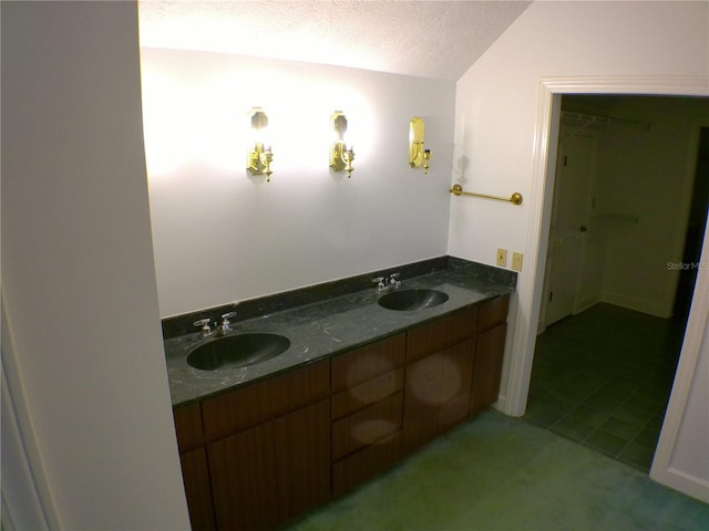 bathroom featuring a textured ceiling, vanity, and vaulted ceiling