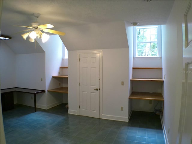 additional living space featuring lofted ceiling, built in desk, and ceiling fan