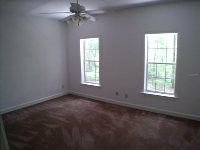 carpeted spare room featuring ceiling fan and plenty of natural light