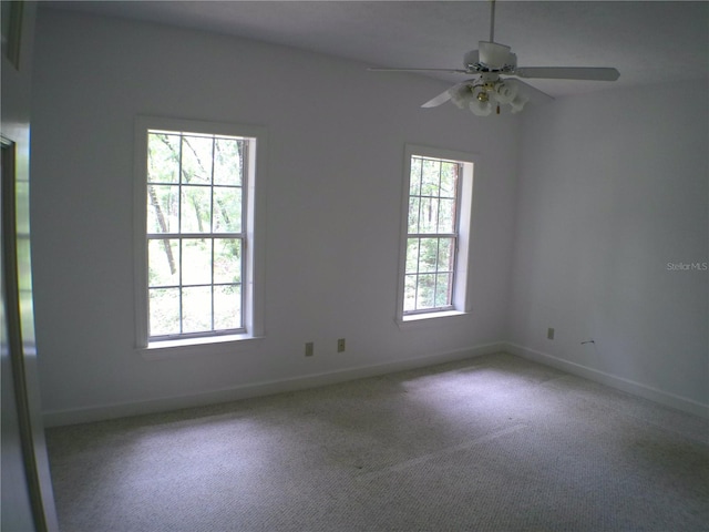 empty room featuring a wealth of natural light, ceiling fan, and light colored carpet