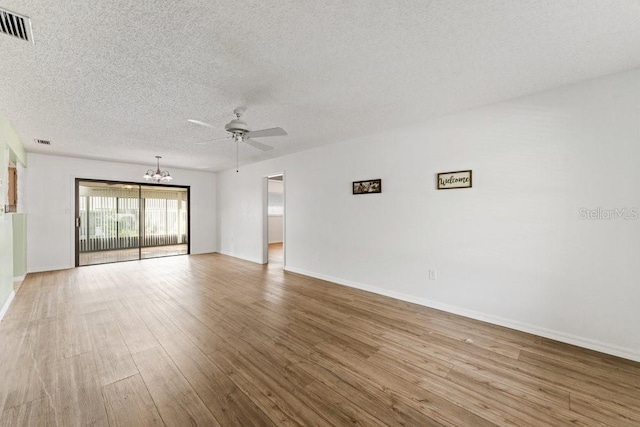 empty room featuring ceiling fan with notable chandelier, hardwood / wood-style floors, and a textured ceiling