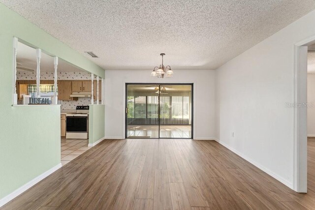 interior space featuring light hardwood / wood-style floors, a textured ceiling, and a notable chandelier