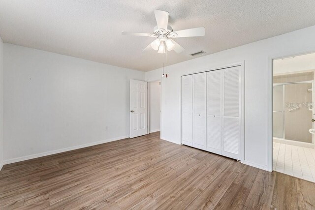 unfurnished bedroom featuring light wood-type flooring, ceiling fan, a textured ceiling, and a closet