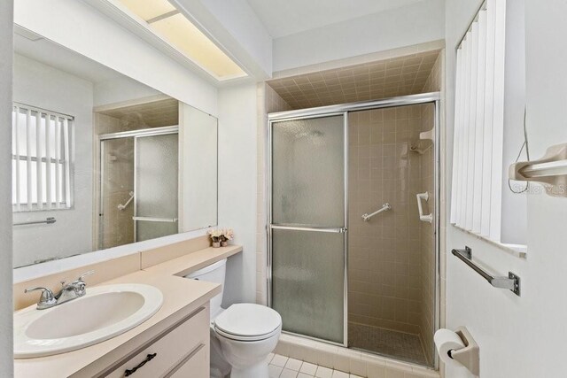 bathroom with toilet, vanity, an enclosed shower, and tile patterned flooring