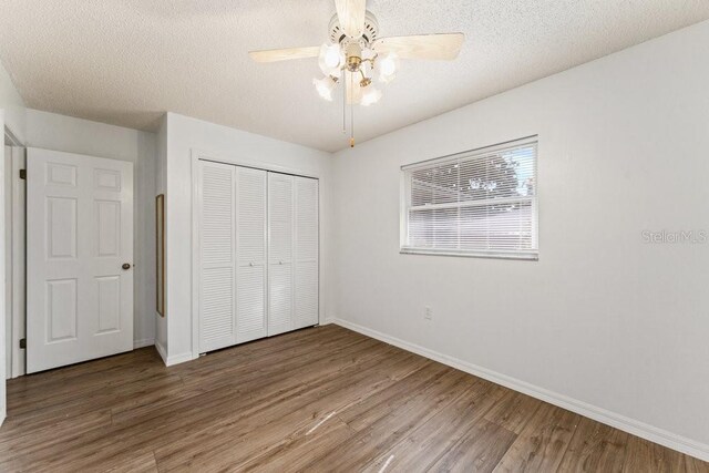 unfurnished bedroom featuring ceiling fan, a textured ceiling, wood-type flooring, and a closet