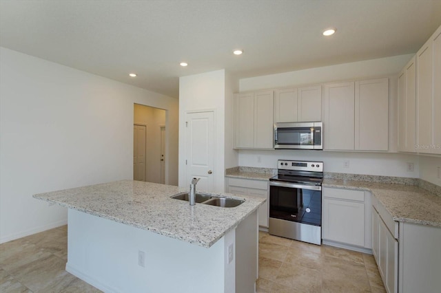 kitchen featuring light stone countertops, stainless steel appliances, a kitchen island with sink, sink, and white cabinetry