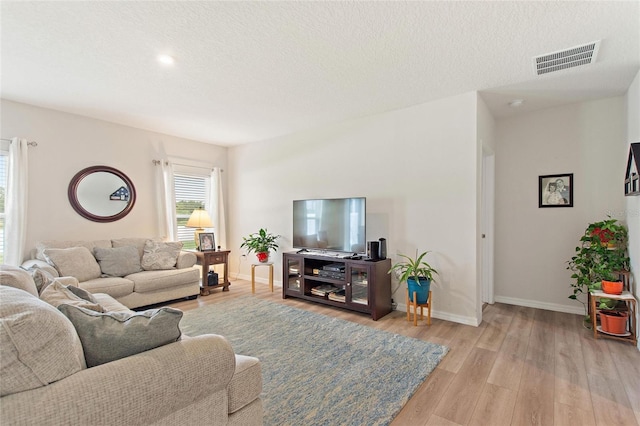 living room with a textured ceiling and light wood-type flooring