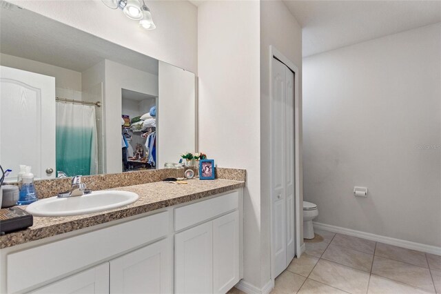 bathroom with tile flooring, toilet, and large vanity