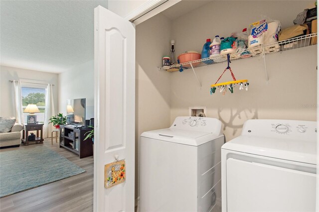 washroom with hookup for a washing machine, hardwood / wood-style flooring, a textured ceiling, and washing machine and dryer